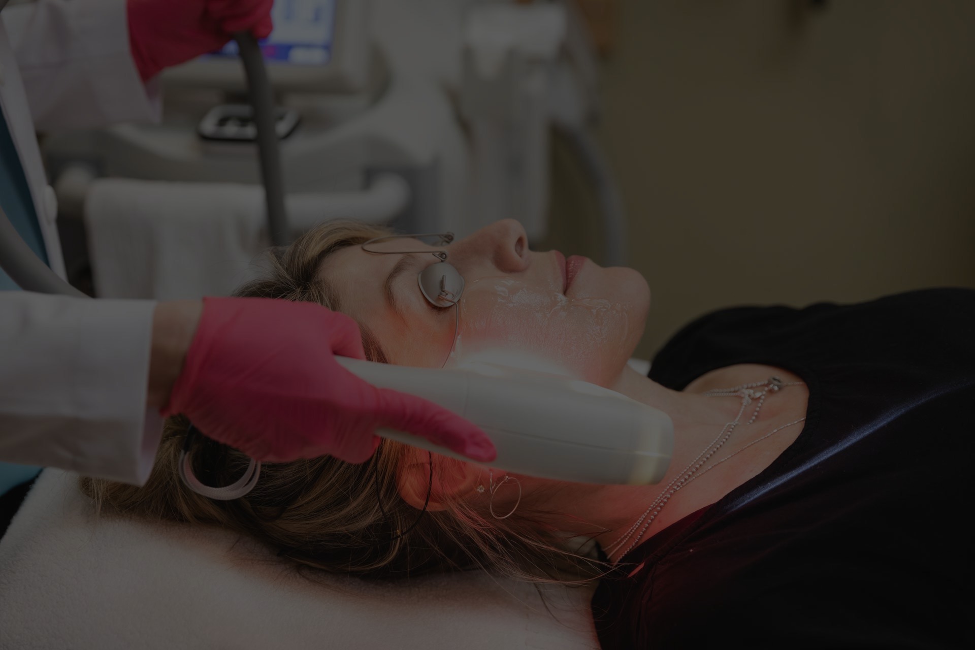 Provider passing a skin tightening handpiece along a client's jaw and neck at Catara Med Spa in Algonquin, IL, the client wearing protective eye shields.