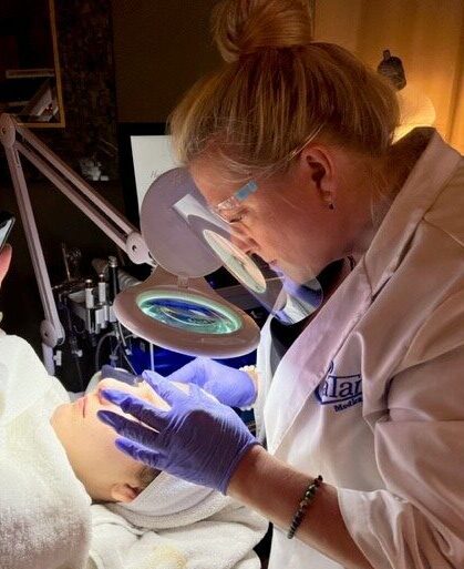 Licensed aesthetician performing a facial treatment at Catara Med Spa in Algonquin, IL using a magnifying lamp and precision techniques.