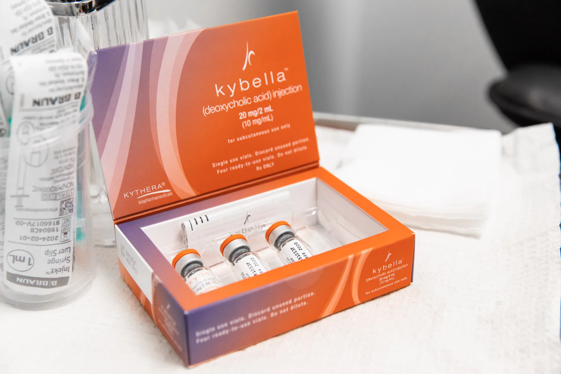 An open Kybella deoxycholic acid injection box with three vials and a syringe laid out for a double chin treatment at Catara Med Spa.