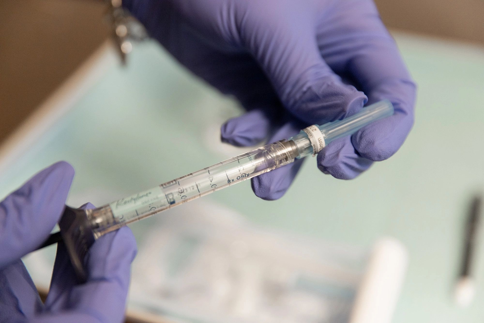 Gloved hands preparing a graduated hyaluronic acid dermal filler syringe on a treatment tray before an injectable appointment to restore facial volume at Catara Med Spa in Algonquin, IL