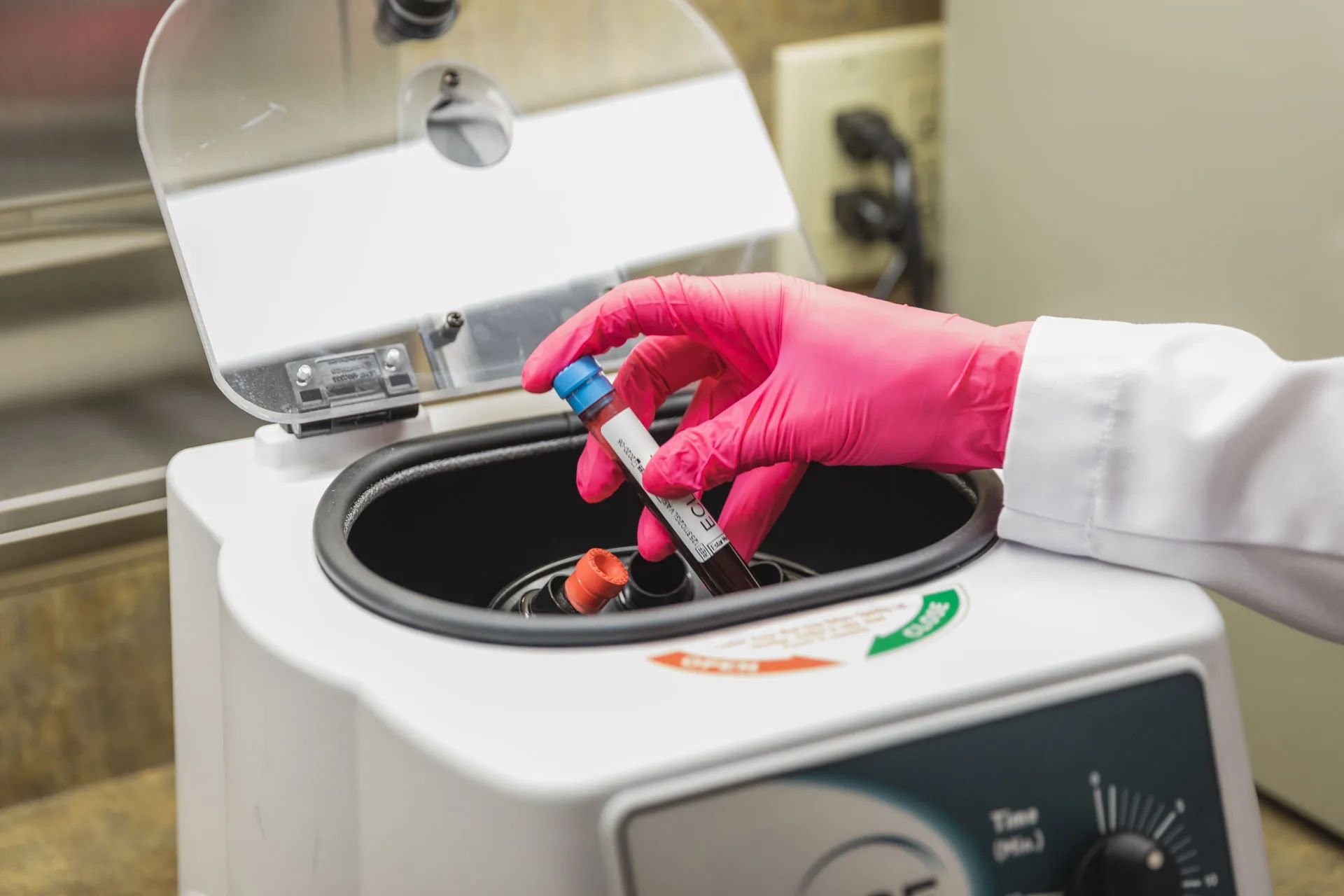 Gloved hand loading a drawn blood tube into a benchtop centrifuge to separate plasma and concentrate platelets before a platelet-rich plasma injection at Catara Med Spa in Algonquin, IL